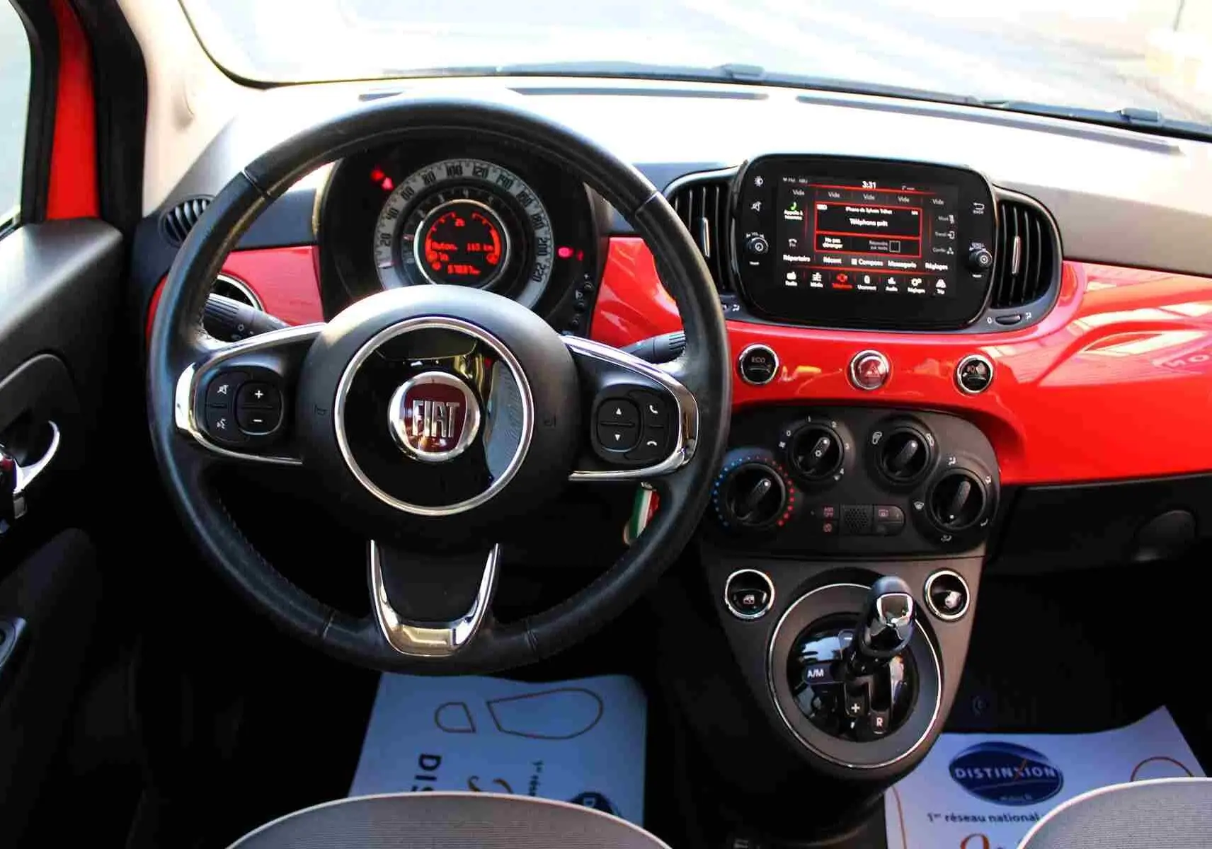 Gros plan sur le volant noir de la Fiat 500C 2018 avec logo rouge FIAT et tableau de bord partiellement visible en arrière-plan.