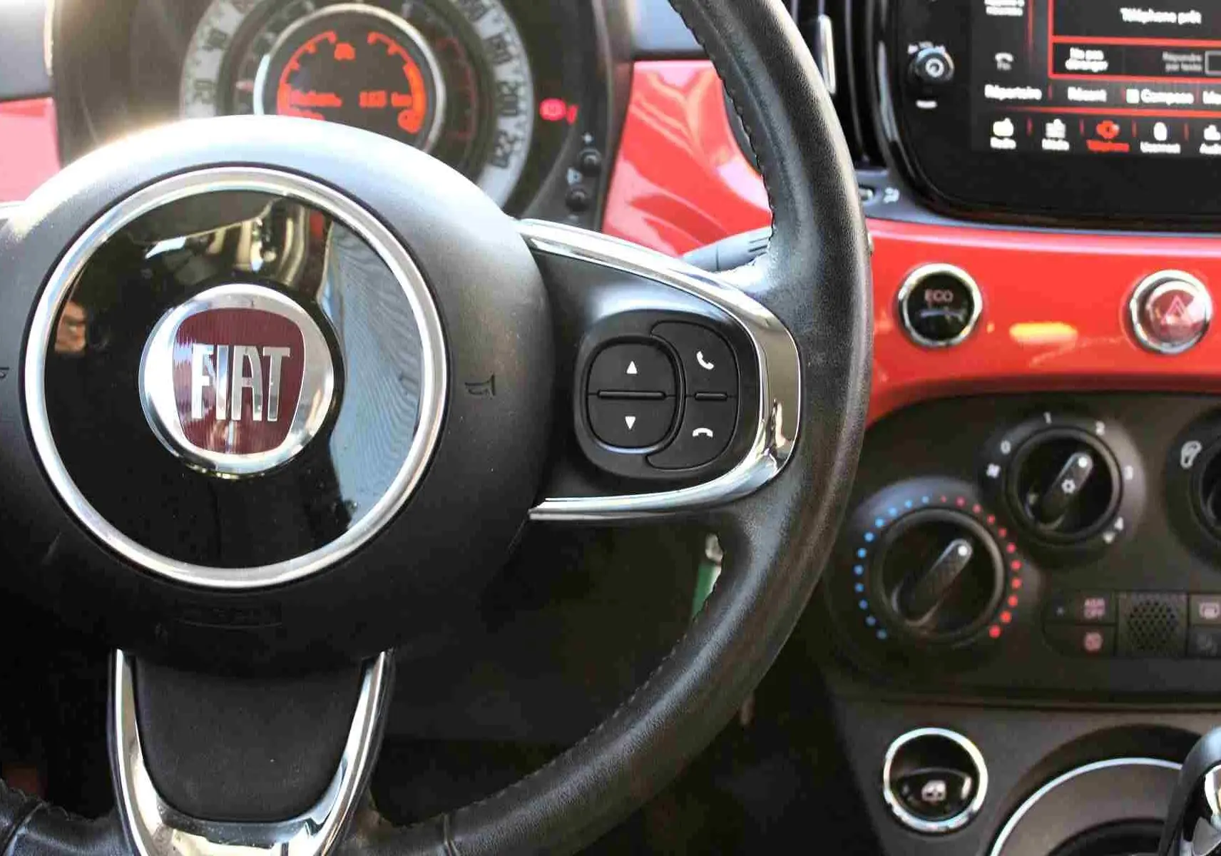 Gros plan sur la console centrale de la Fiat 500C 2018, montrant porte-gobelets, prise 12V, entrée AUX et port USB.