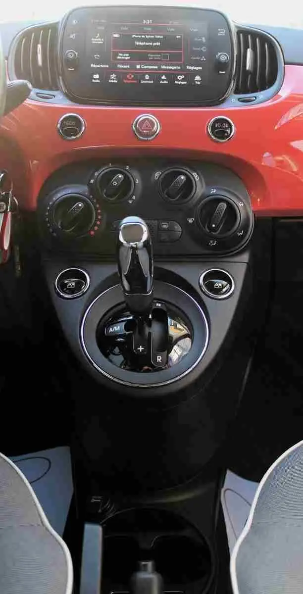 Vue rapprochée du volant et tableau de bord rouge pastel d'une Fiat 500C 2018 avec commandes intégrées au volant.