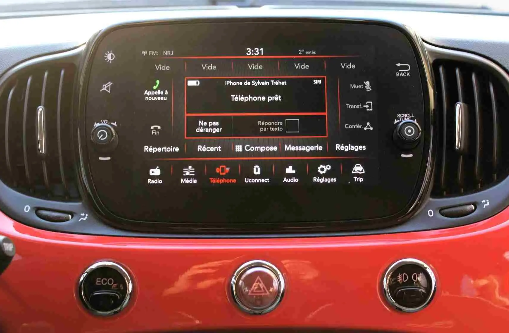 Vue rapprochée du tableau de bord rouge pastel d'une Fiat 500C 2018, avec écran tactile central allumé.