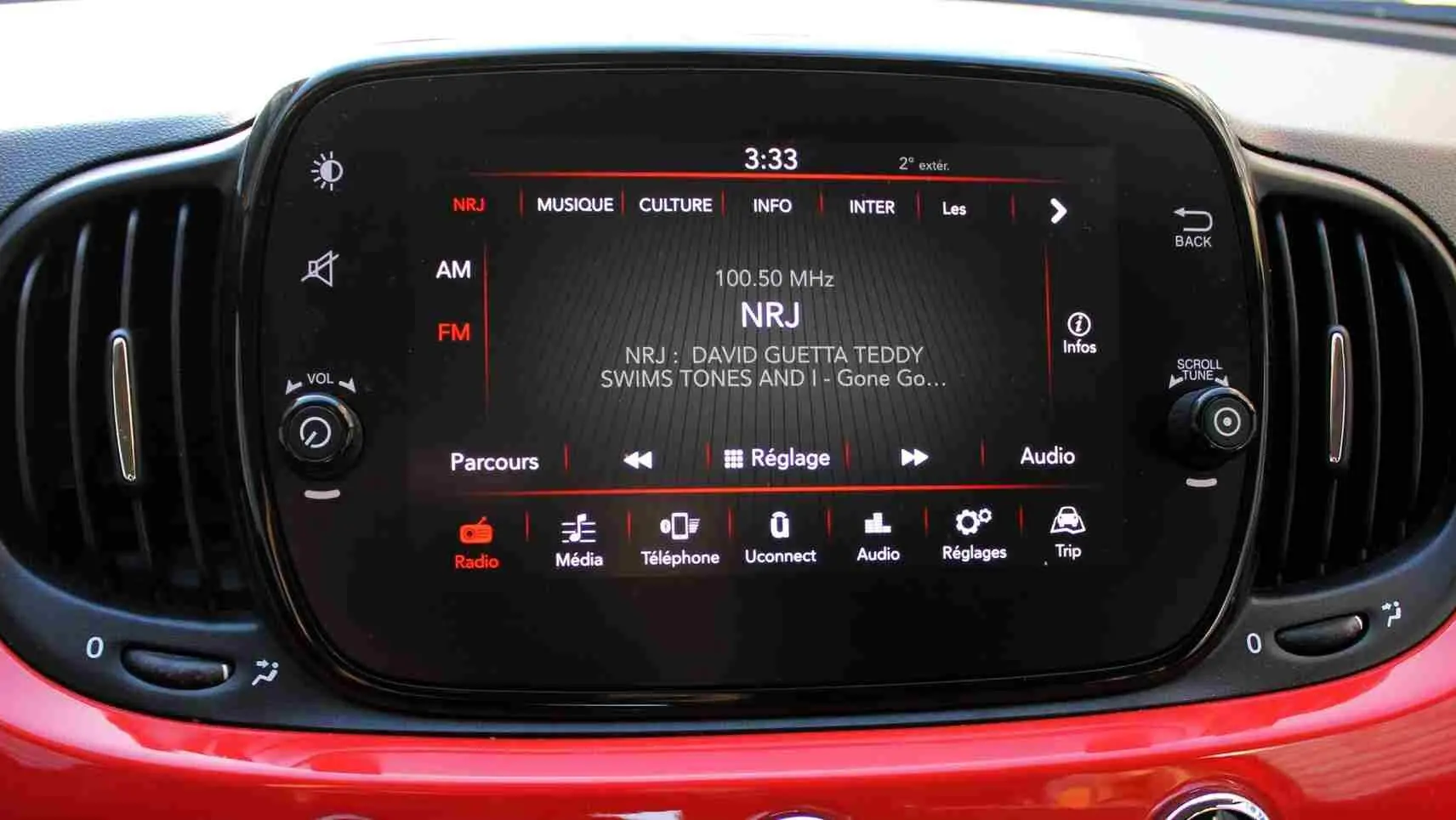 Écran tactile central de la Fiat 500C 2018 en Pastel Coral Red, affichant la radio NRJ en mode FM.