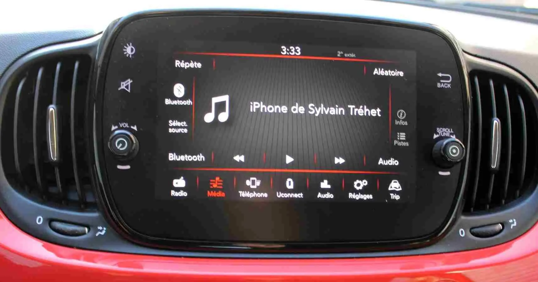 Écran tactile central de la Fiat 500C 2018 en Pastel Coral Red, affichant la connexion Bluetooth avec un iPhone.