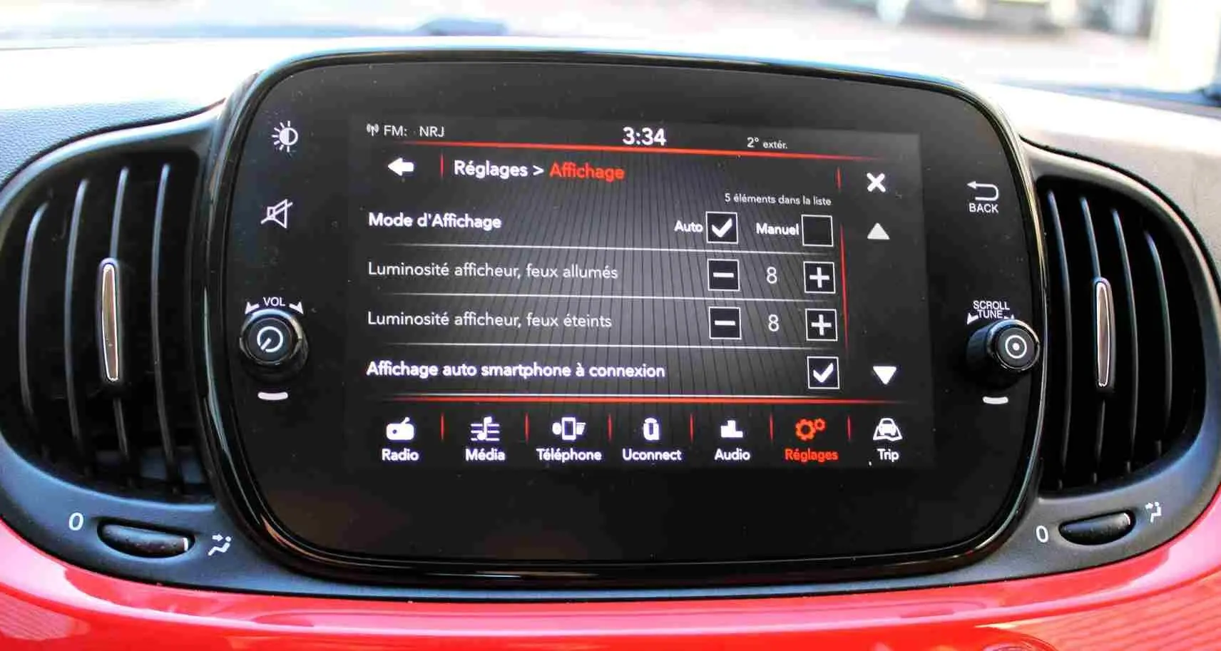 Écran tactile central de la Fiat 500C 2018 en Pastel Coral Red, affichant le menu Réglages et options d’affichage.