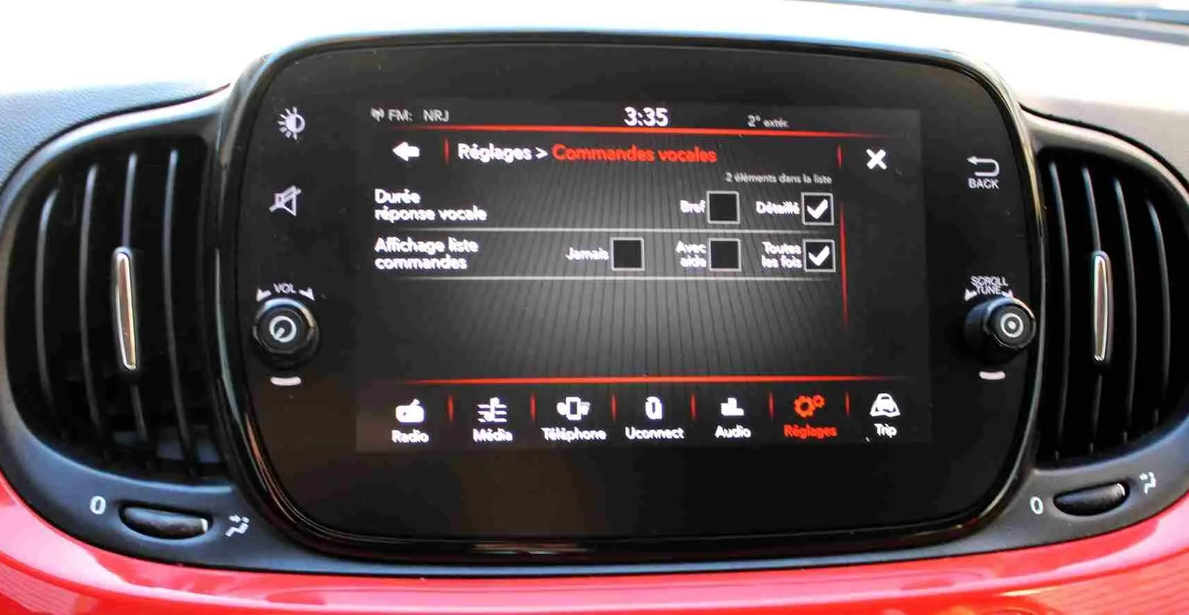 Écran tactile central de la Fiat 500C 2018 en Pastel Coral Red, affichant les réglages des commandes vocales.