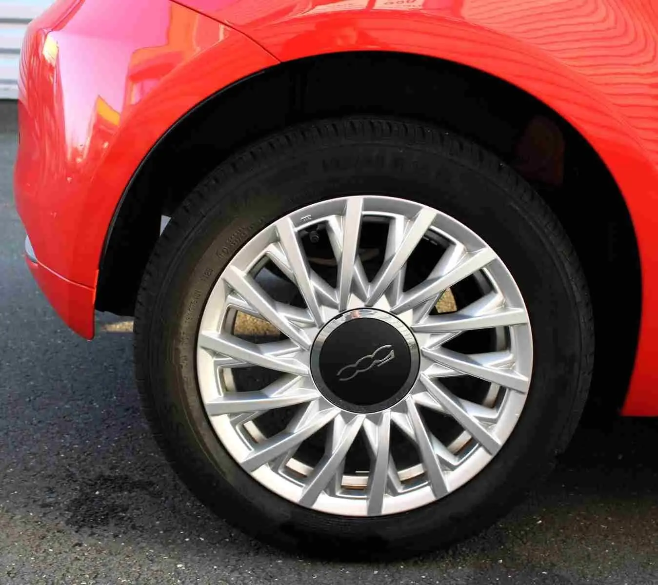 Gros plan sur l'emblème 500C rouge et chrome sur la porte côté droit d'une FIAT 500C Pastel Coral Red.