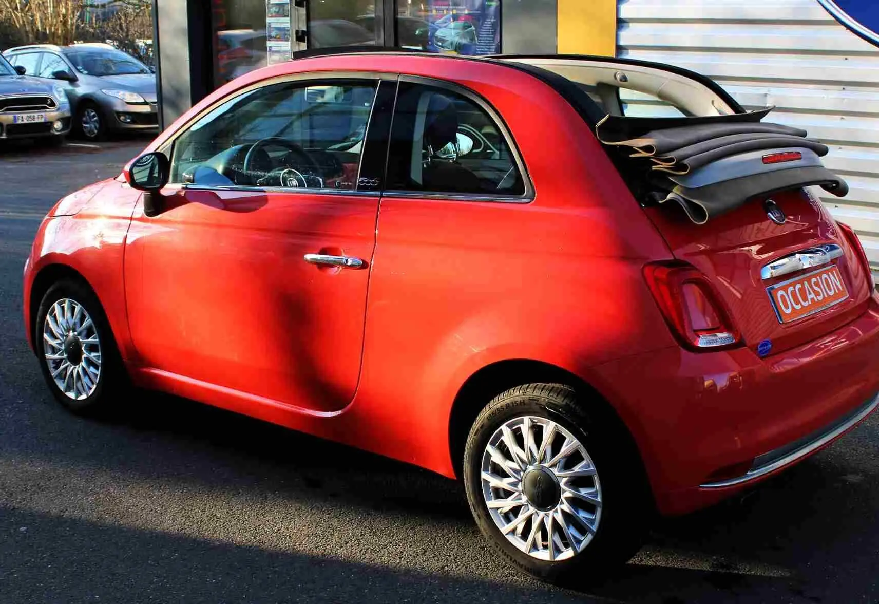 Fiat 500C Pastel Coral Red vue 3/4 avant droit, toit rigide noir, jantes alliage et plaque "OCCASION".