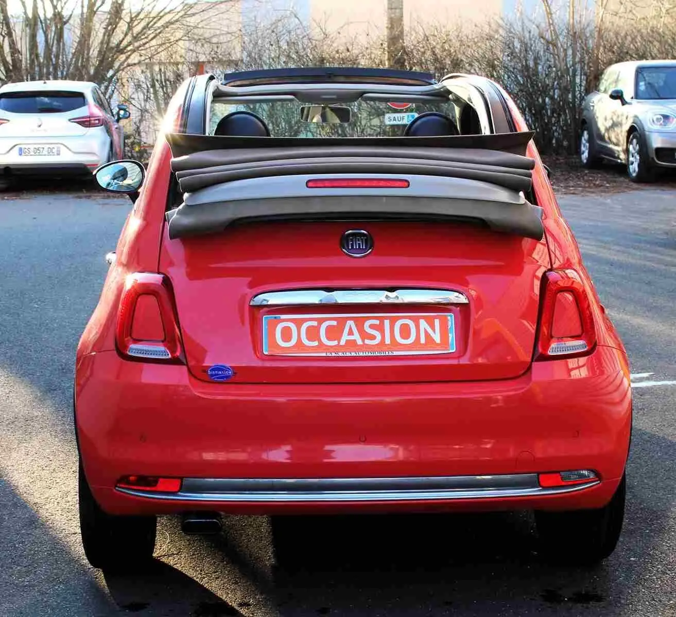 Vue 3/4 arrière droite d'une FIAT 500C 2018 pastel coral red avec toit ouvrant replié et plaque "OCCASION".