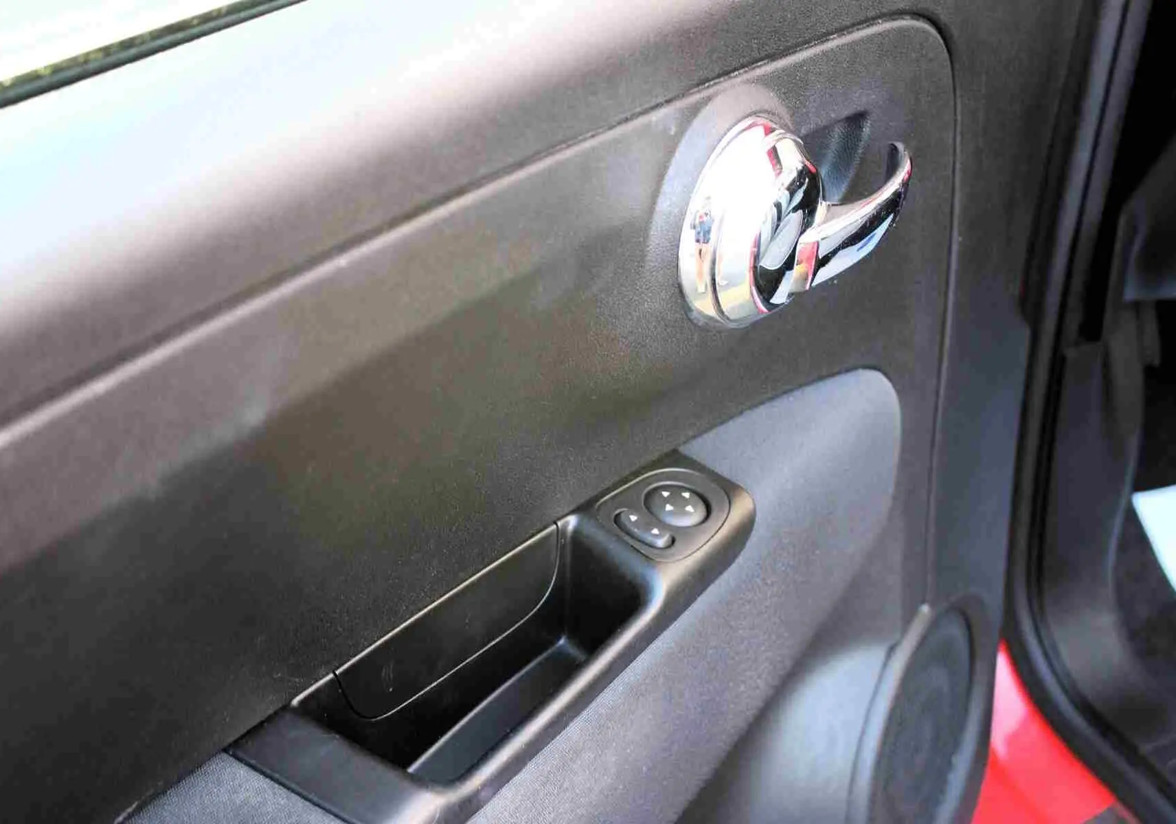 Intérieur de la Fiat 500C 2018 en vue avant, tableau de bord rouge pastel coral avec volant noir et écran tactile.