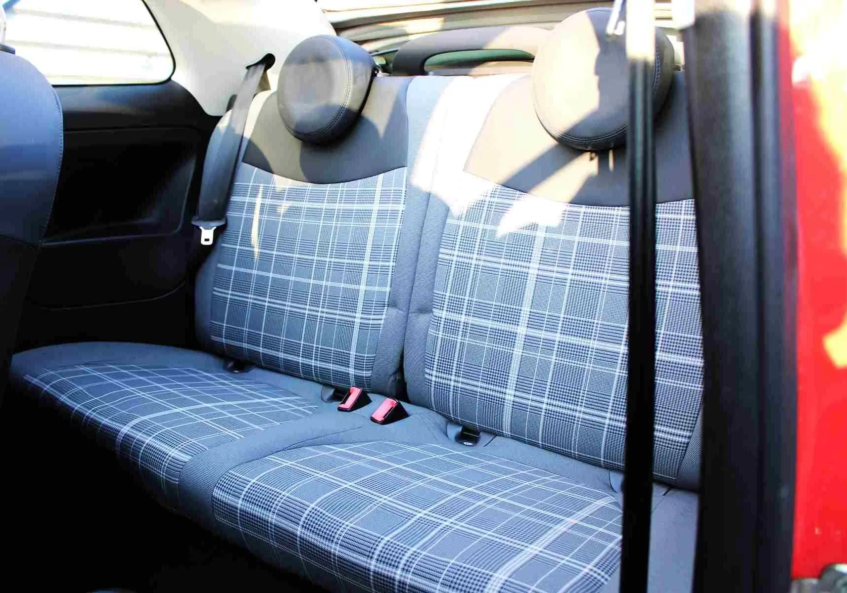Vue intérieure sur la banquette arrière à motifs carreaux gris d'une FIAT 500C rouge Pastel Coral Red de 2018.