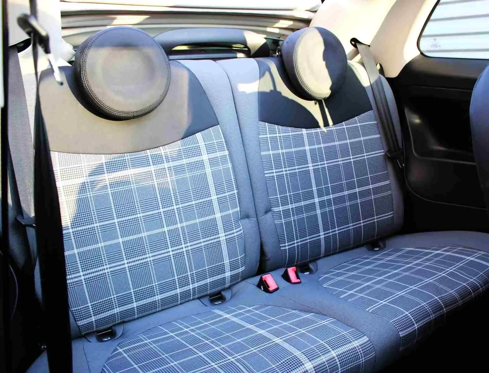 Fiat 500C Pastel Coral Red vue 3/4 avant droit, toit noir, devant un mur métallique avec logo Distinxion.