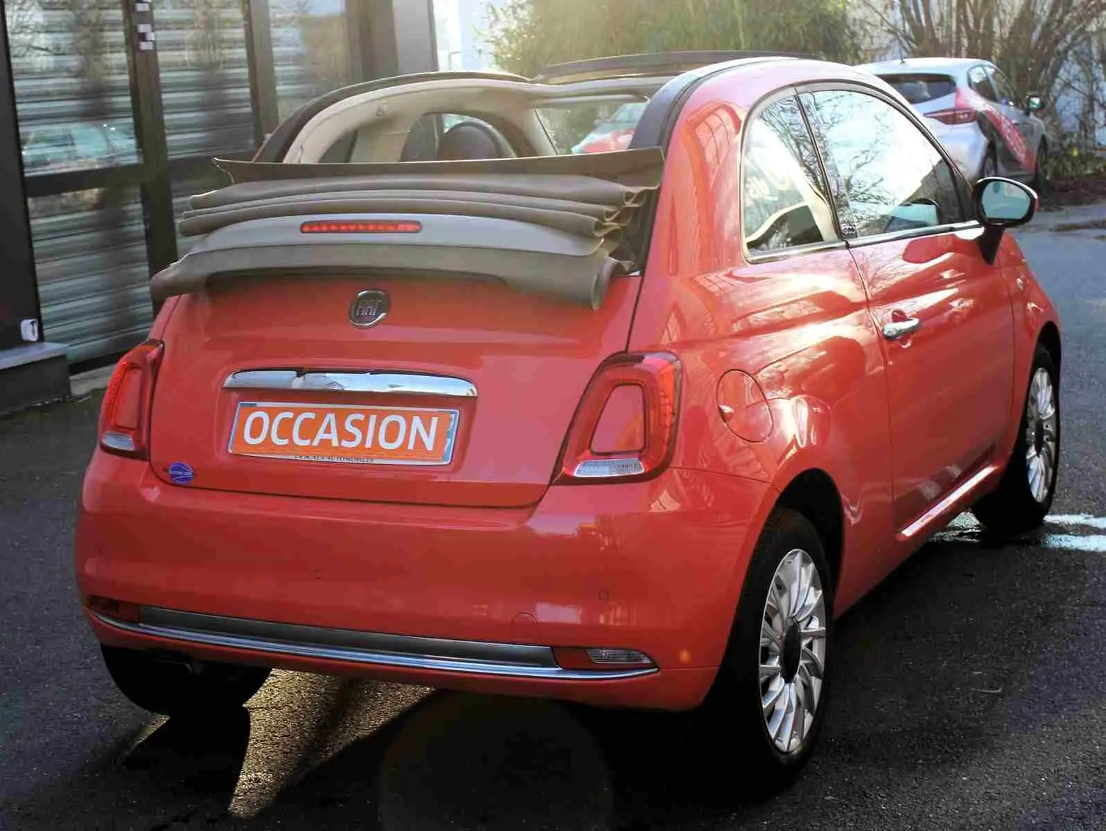 Profil côté gauche d'une FIAT 500C 2018 rouge Pastel Coral avec jantes alliage et toit rigide fermé.