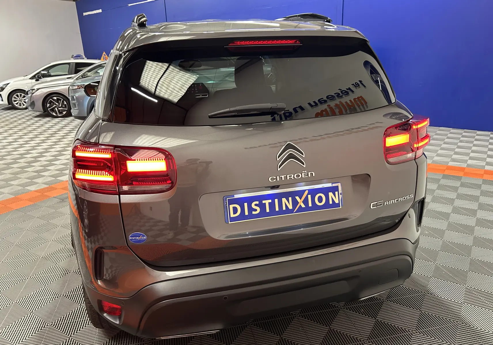 Vue arrière d’un Citroën C5 Aircross gris Platinium avec feux allumés dans un showroom intérieur.