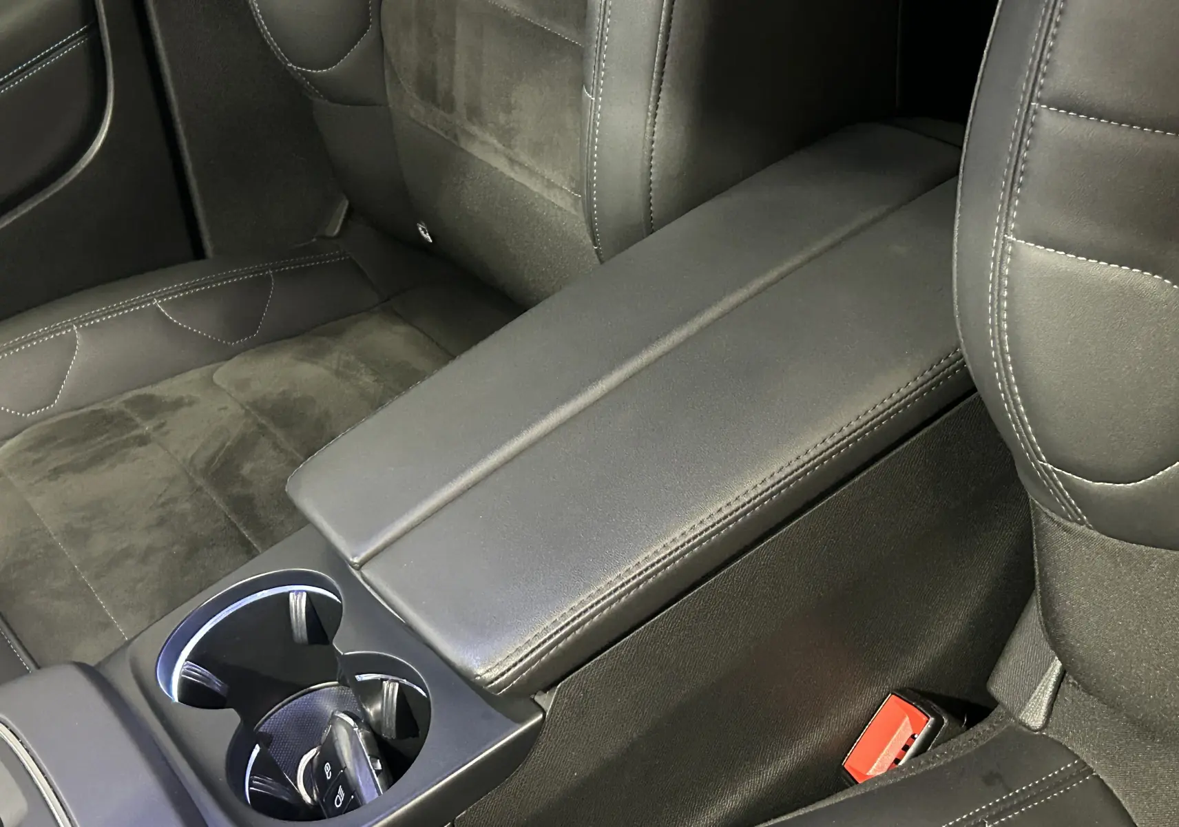 Gros plan sur l'accoudoir central et les sièges noirs en cuir et alcantara de la Citroën C5 Aircross 2023.