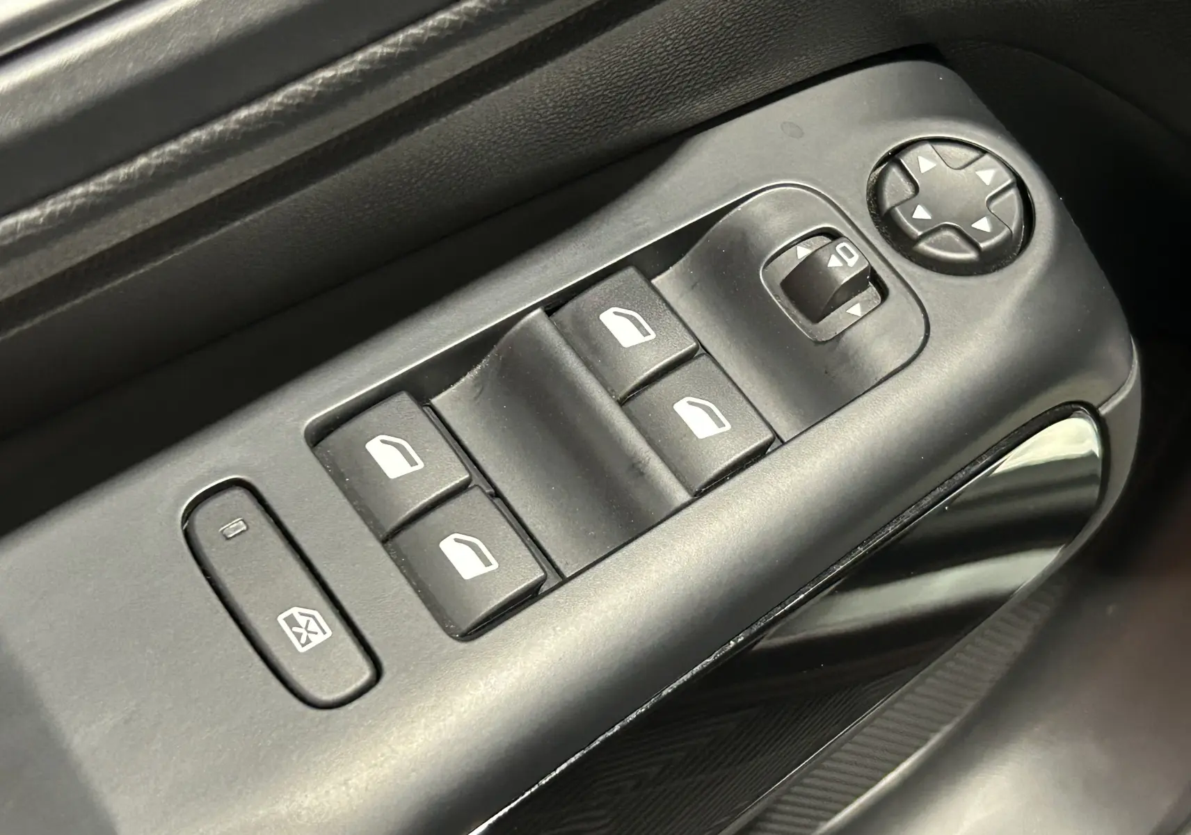 Gros plan sur les commandes de lève-vitres et réglage des rétroviseurs côté conducteur d’une Citroën C5 Aircross gris Platinium.