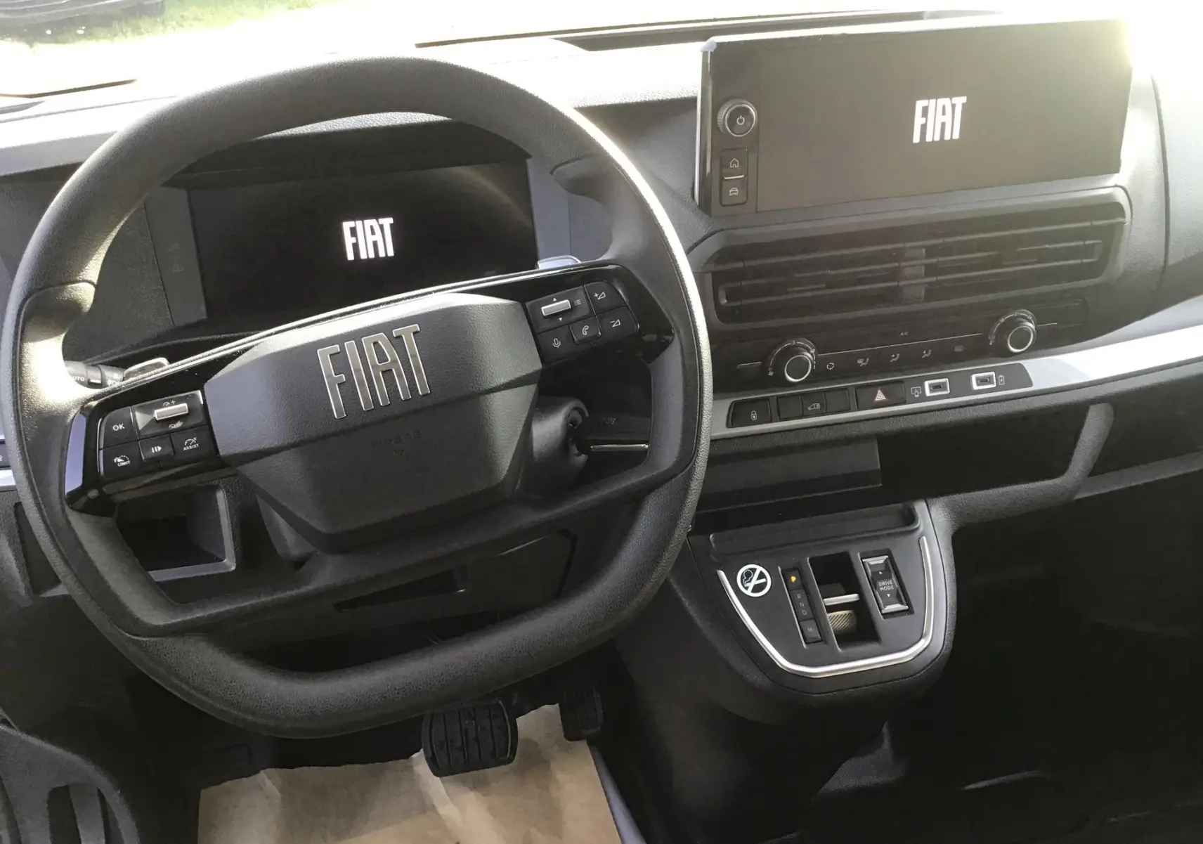 Vue intérieure centrée sur le volant et le tableau de bord numérique du Fiat Scudo Fourgon blanc, avec écran tactile et commandes intégrées.