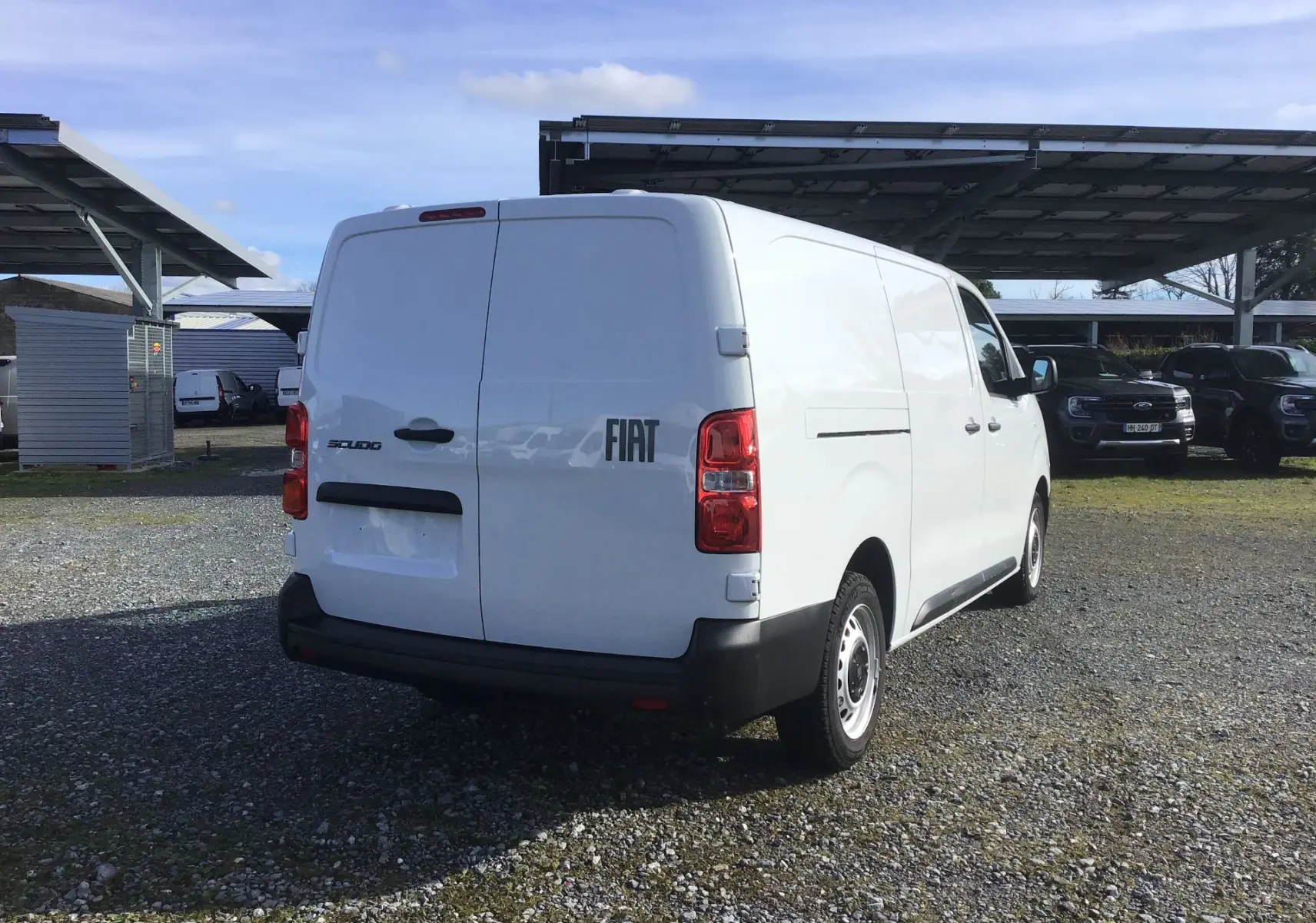 Vue 3/4 arrière droite d’un fourgon FIAT Scudo blanc 2024 avec porte arrière double et pare-chocs noir.
