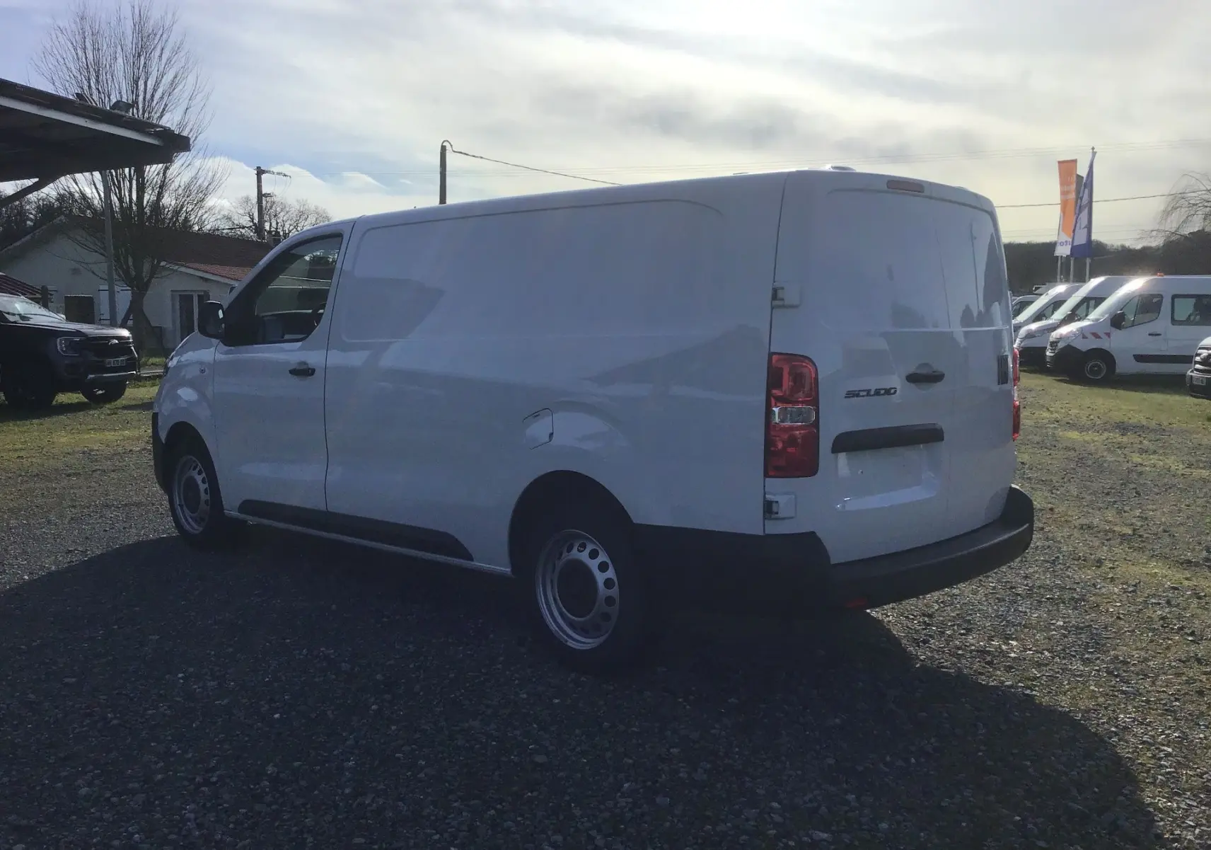 Fiat Scudo Fourgon blanc vu en 3/4 arrière droit, avec porte latérale coulissante et jantes acier simples.