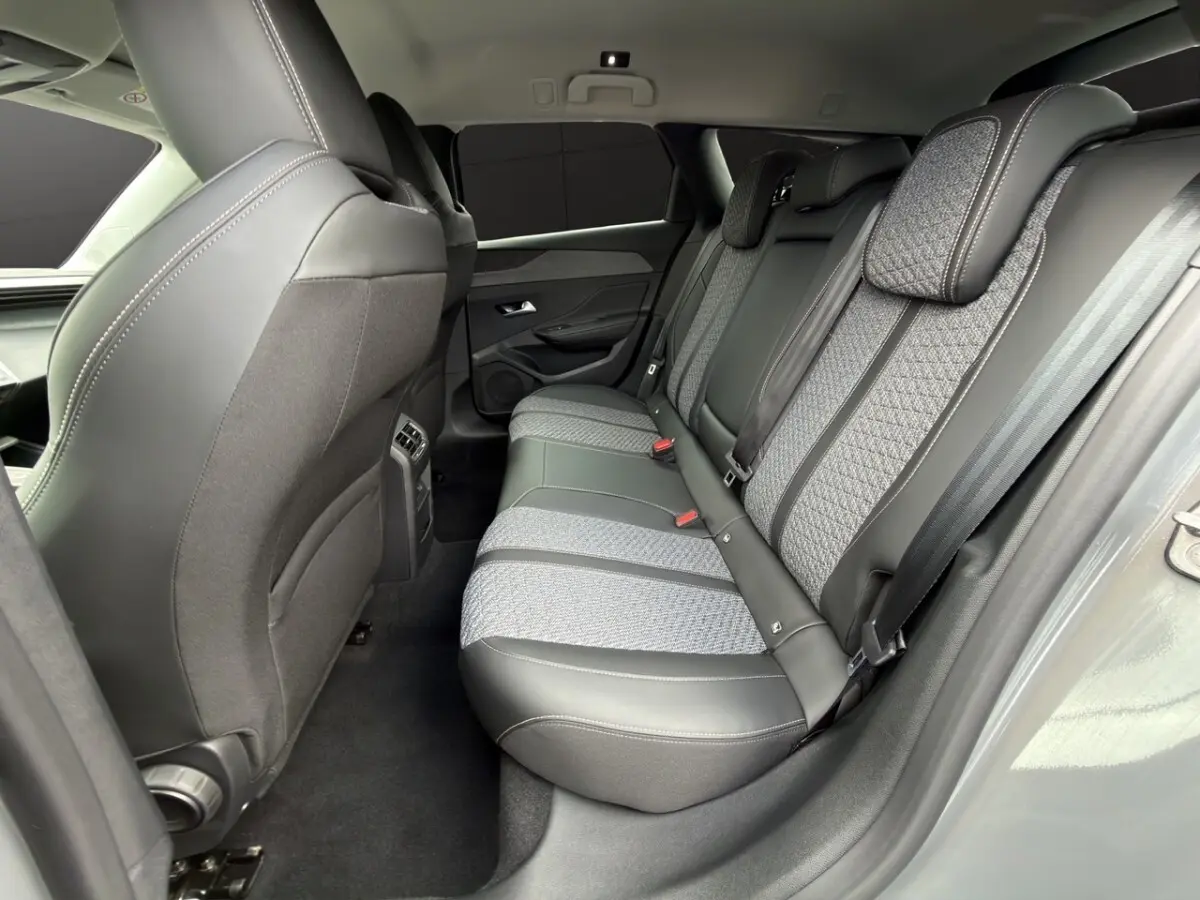 Vue intérieure arrière côté droit des sièges arrière en tissu et cuir gris de la Peugeot 308 Hybrid 145 e-DCS6 Allure 2025.