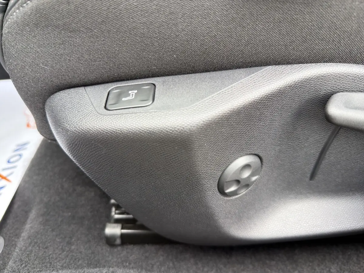 Détail de la commande de réglage manuel du siège avant en tissu gris foncé dans une Peugeot 308 Hybrid 145 e-DCS6 Allure.