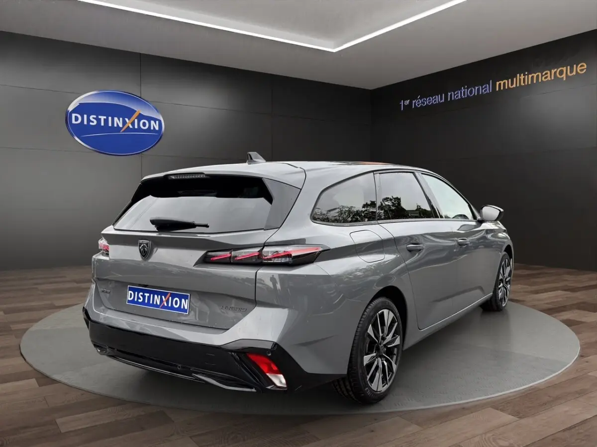 Vue 3/4 arrière droite d'une Peugeot 308 Hybrid gris foncé avec feux arrière LED et jantes alliage distinctives.