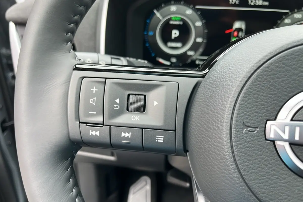 Gros plan sur le volant cuir multifonctions gris du Nissan Qashqai E-Power 205 Tekna Plus avec commandes intégrées.