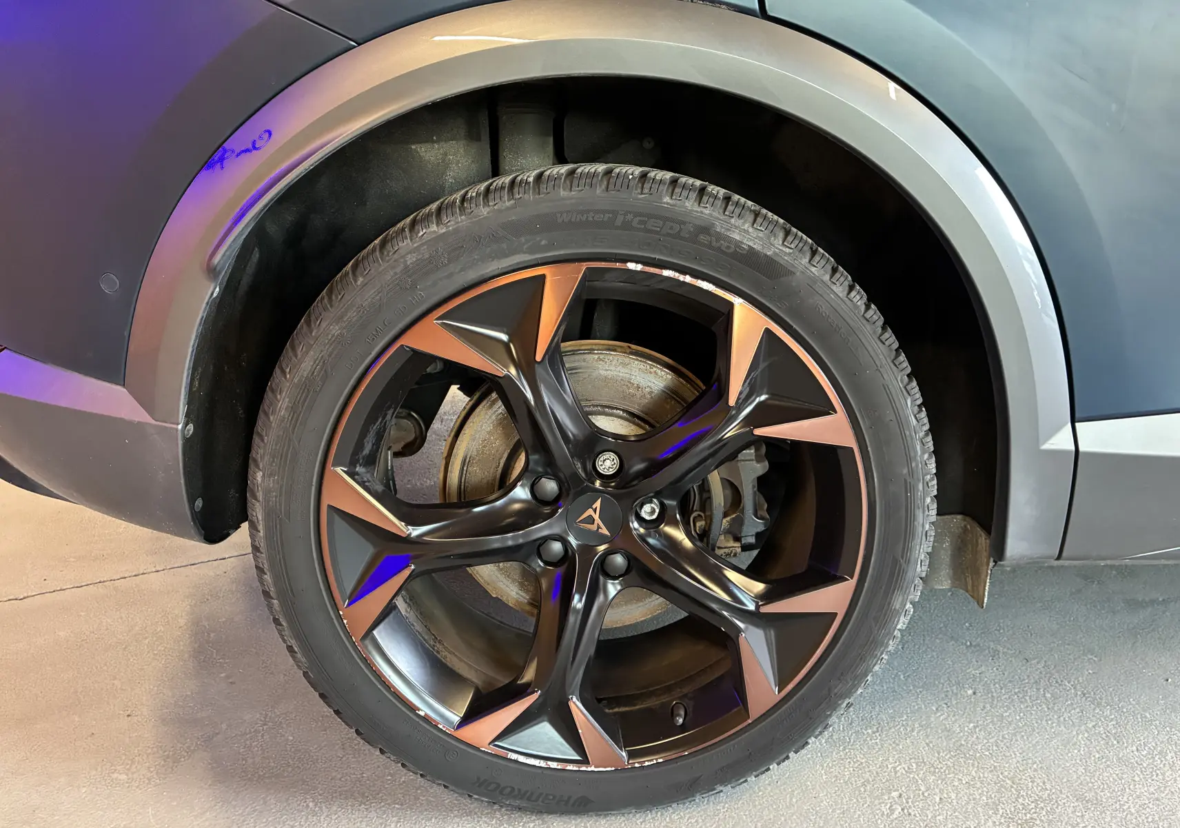 Gros plan sur la jante alu bicolore noir et cuivre du côté arrière droit d'une CUPRA Formentor bleu 2023.