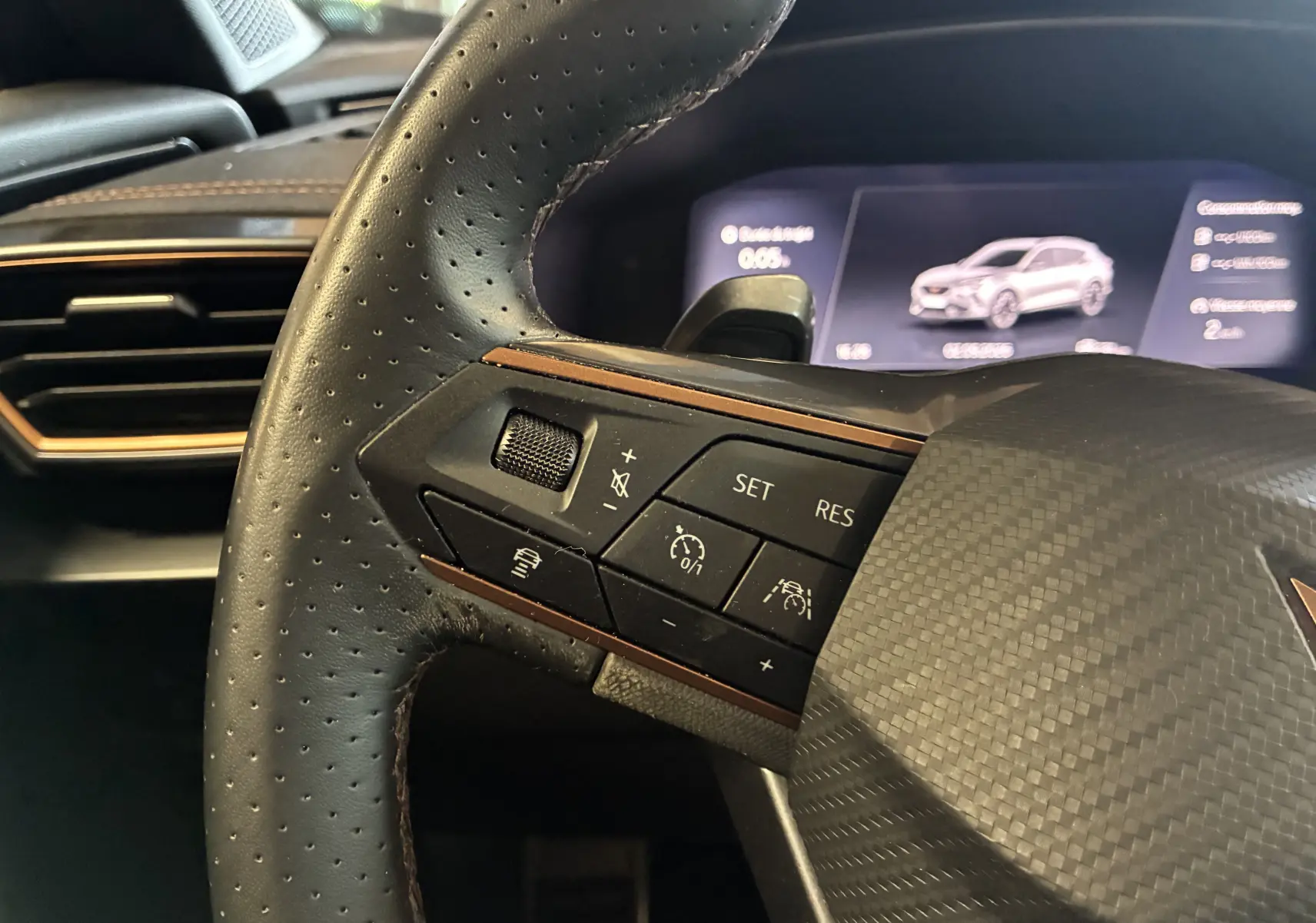 Gros plan sur le volant sport perforé du CUPRA Formentor 1.4 e-Hybrid 2023 avec commandes multifonctions et tableau de bord numérique.