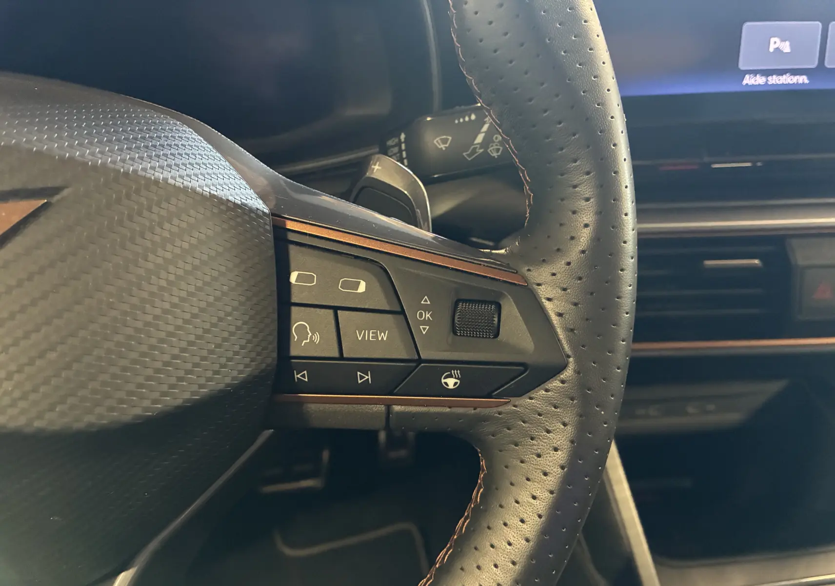 Gros plan sur le volant sport en cuir perforé avec commandes multifonctions et surpiqûres cuivre du CUPRA Formentor bleu.