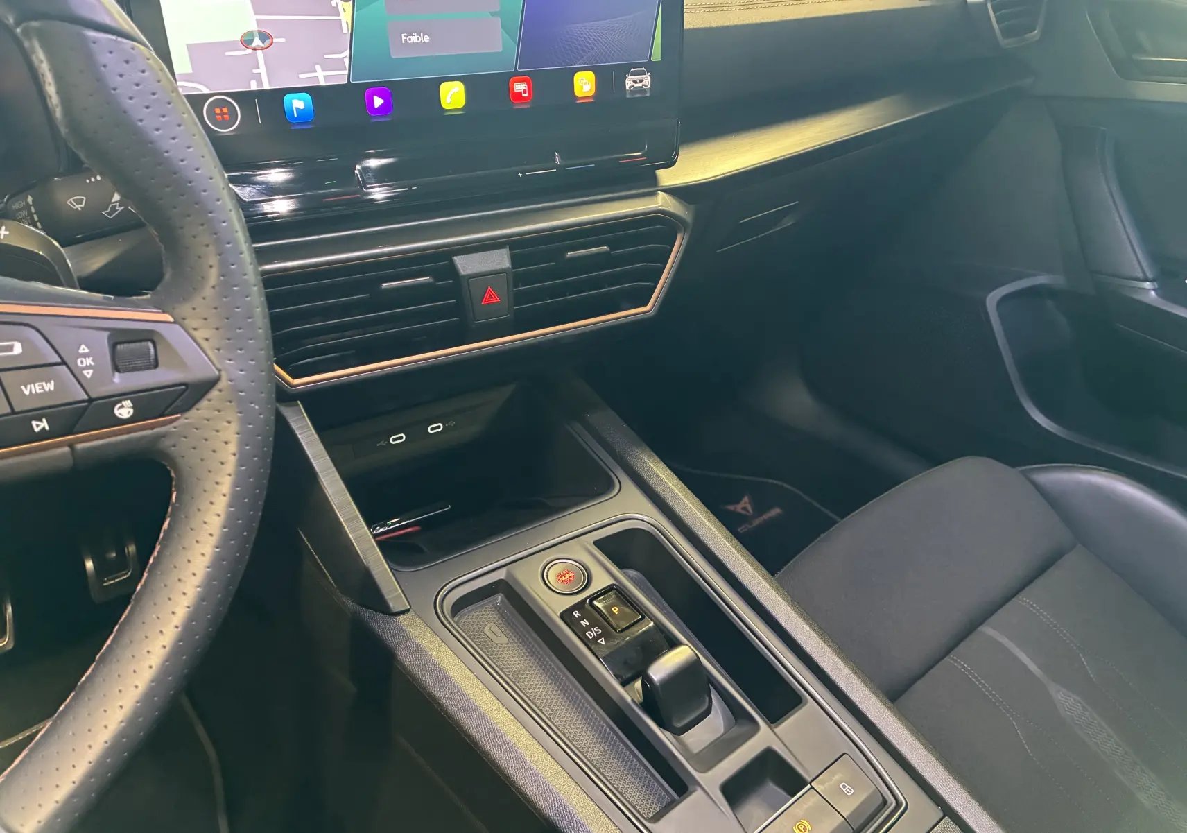 Vue intérieure centrée sur la console centrale et volant perforé du Cupra Formentor 1.4 e-Hybrid 2023, finition noire.