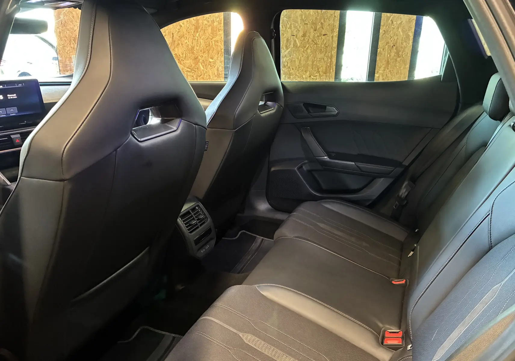 Vue intérieure arrière de la CUPRA Formentor 1.4 e-Hybrid 2023, sièges sport noirs en tissu et similicuir avec surpiqûres copper.