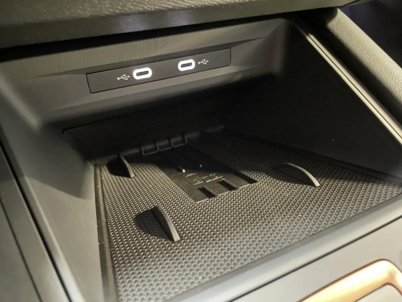 Gros plan sur l'espace de rangement central avec deux ports USB-C éclairés dans l'habitacle noir du CUPRA Leon 2026.