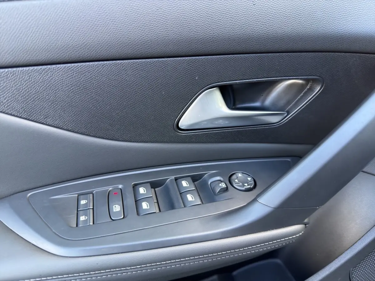 Gros plan sur la commande des vitres et la poignée intérieure côté conducteur de la Peugeot 308 Hybrid gris foncé.