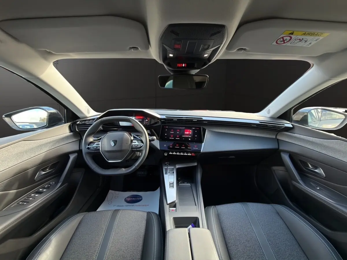 Vue intérieure avant centrée du tableau de bord et volant cuir de la Peugeot 308 Hybrid 145 e-DCS6 Allure 2025.