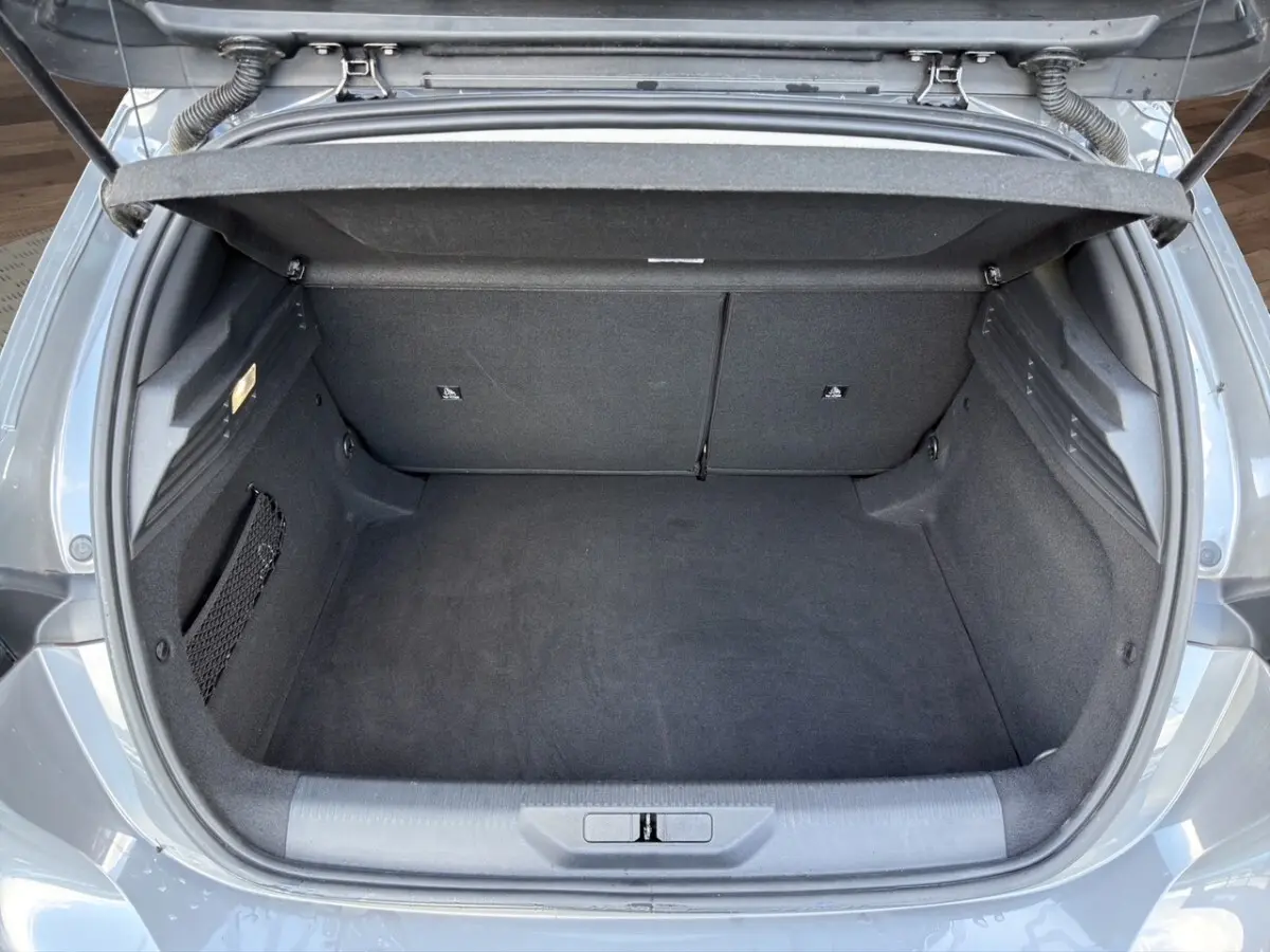 Coffre ouvert vu de dessus d’une Peugeot 308 Hybrid 145 gris foncé, espace de rangement propre et spacieux.