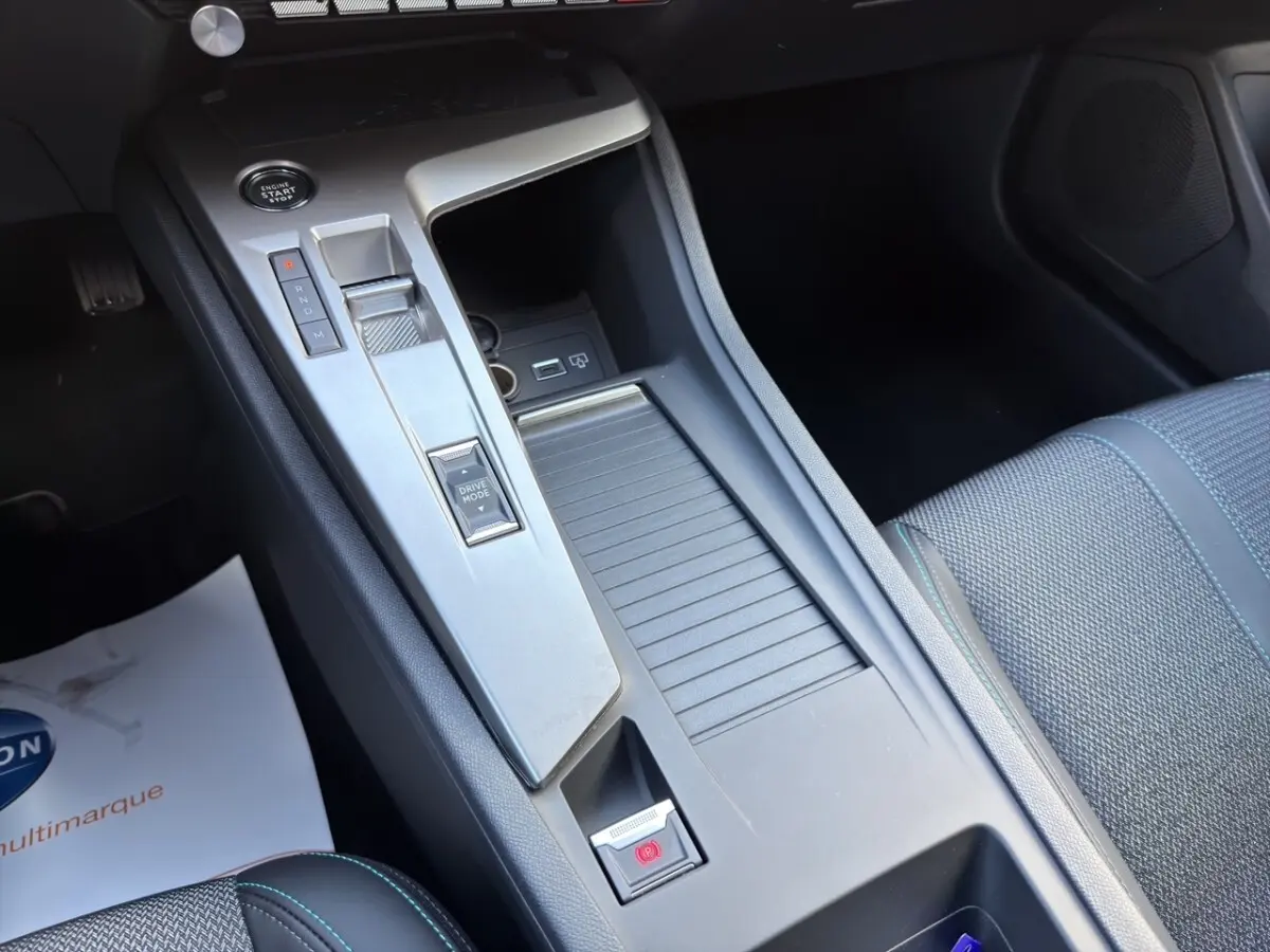 Vue rapprochée de la console centrale intérieure de la Peugeot 308 Hybrid gris foncé, avec bouton start/stop et sélecteur de mode de conduite.