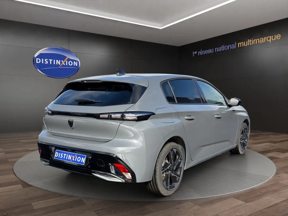 Vue 3/4 arrière droite d'une Peugeot 308 Hybrid 145 gris foncé avec feux arrière LED et jantes alliage noires.