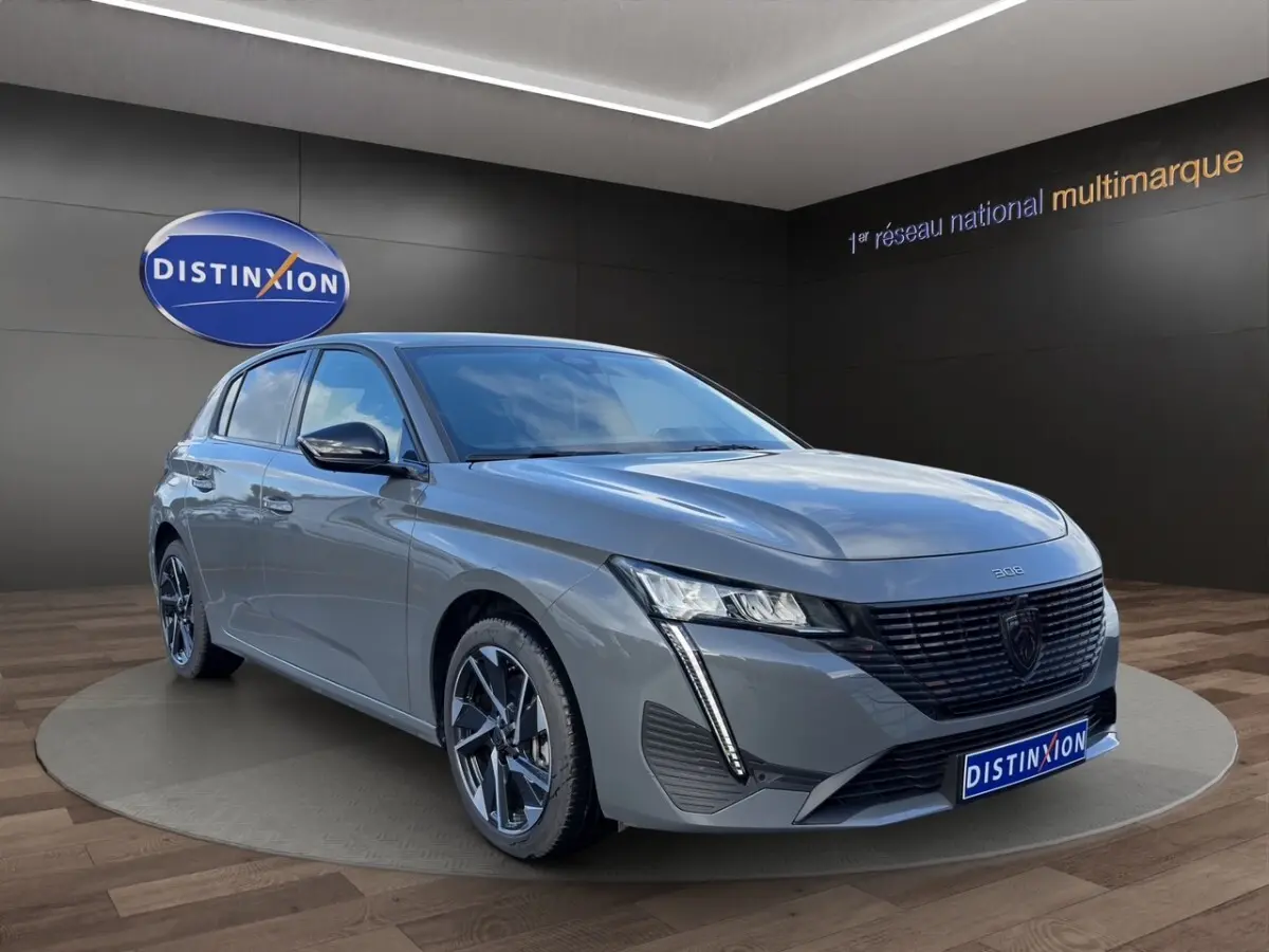 Peugeot 308 Hybrid gris foncé vue 3/4 avant droit, avec calandre noire et phares LED distinctifs.