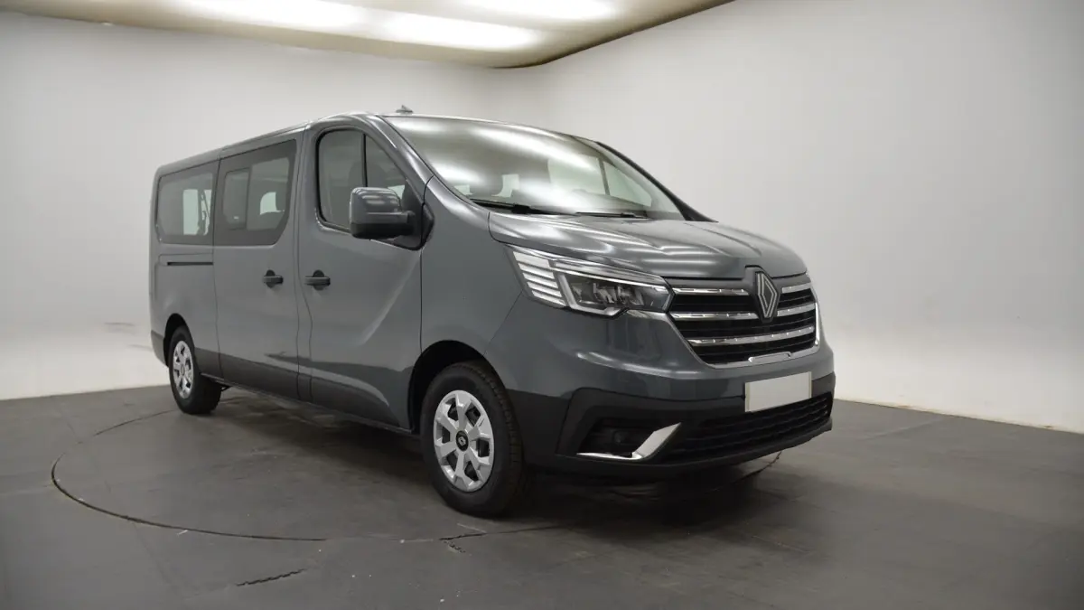 Renault Trafic Fourgon gris clair en 3/4 avant droit, avec calandre chromée et feux LED distinctifs.