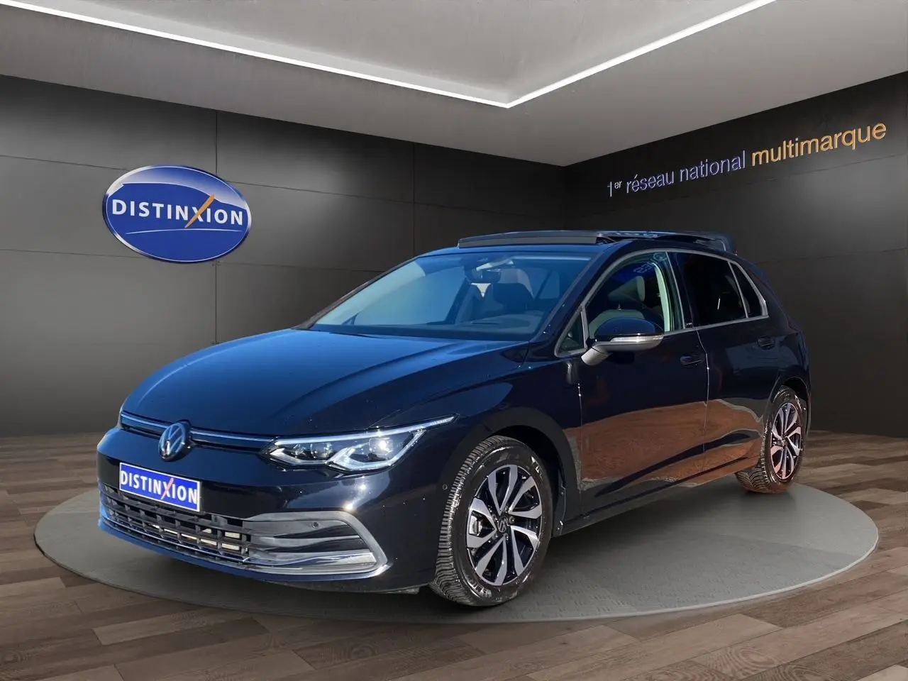 Volkswagen Golf VIII noire vue 3/4 avant droit avec toit panoramique et jantes alliage en showroom.