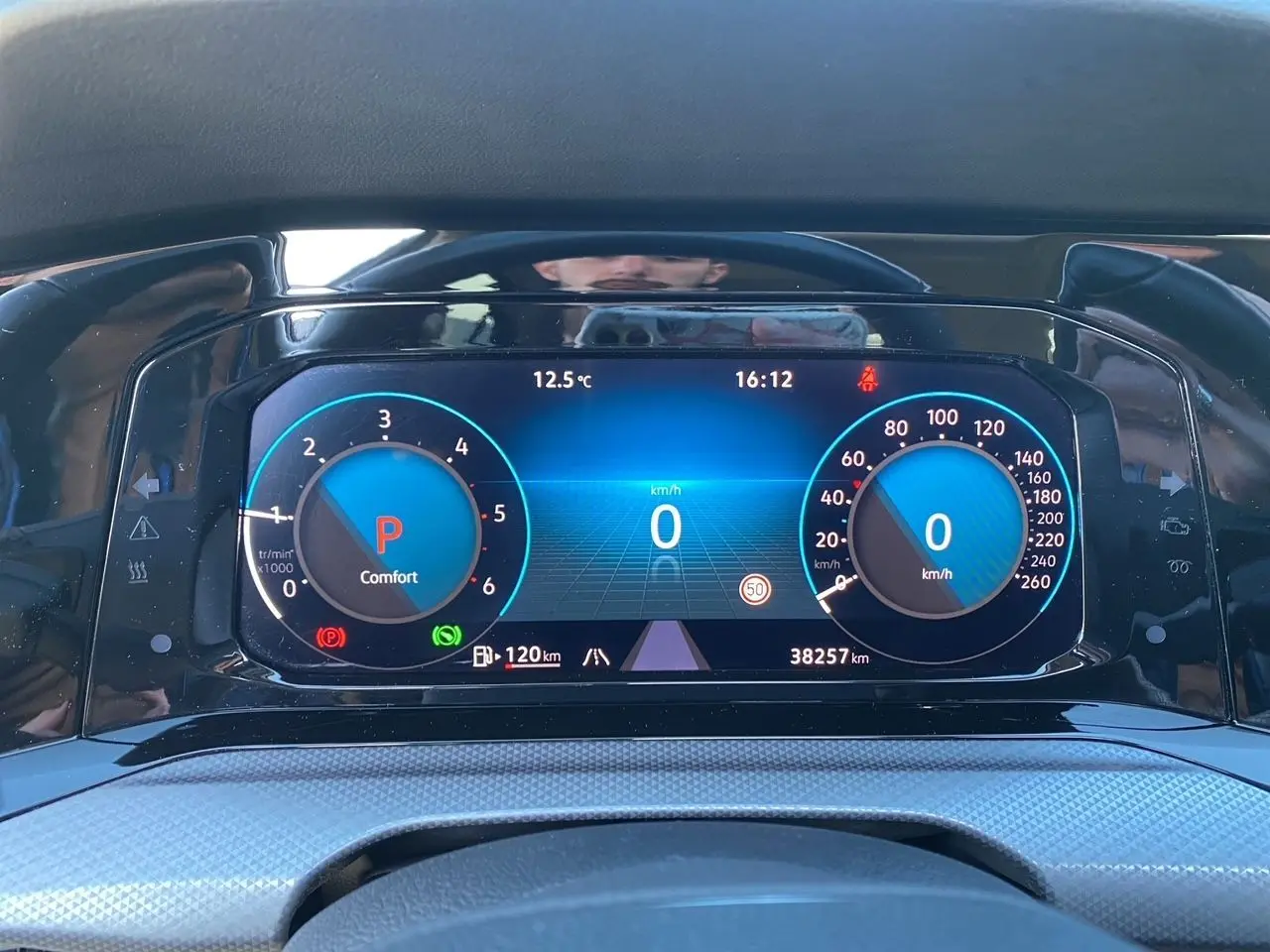 Vue rapprochée du tableau de bord numérique bleu de la Volkswagen Golf VIII noire, affichant vitesse et régime moteur à l'arrêt.