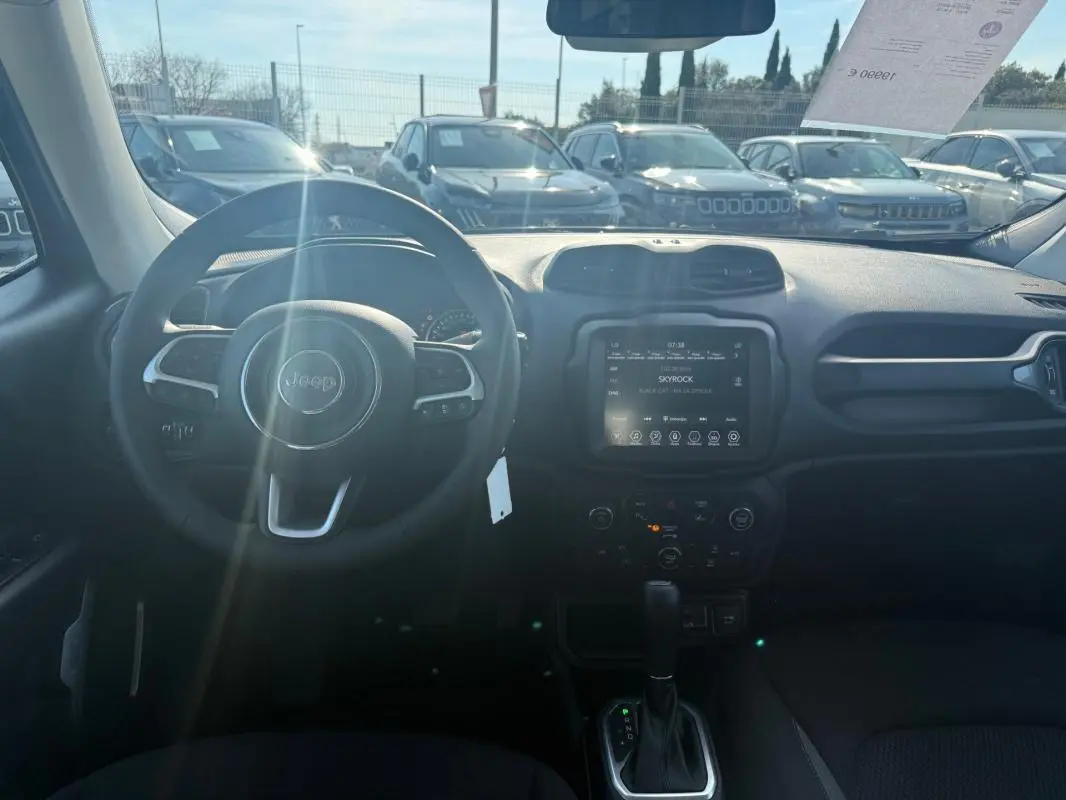 Vue intérieure du tableau de bord du Jeep Renegade 2023 avec écran tactile et volant multifonction, lumière naturelle entrant par le pare-brise.