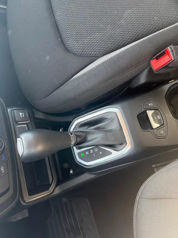 Gros plan sur la console centrale du Jeep Renegade bleu 2023, montrant le levier de vitesse automatique et le siège conducteur noir.