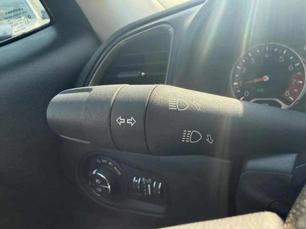 Gros plan sur la commande des clignotants et phares dans l’habitacle du Jeep Renegade bleu 2023.