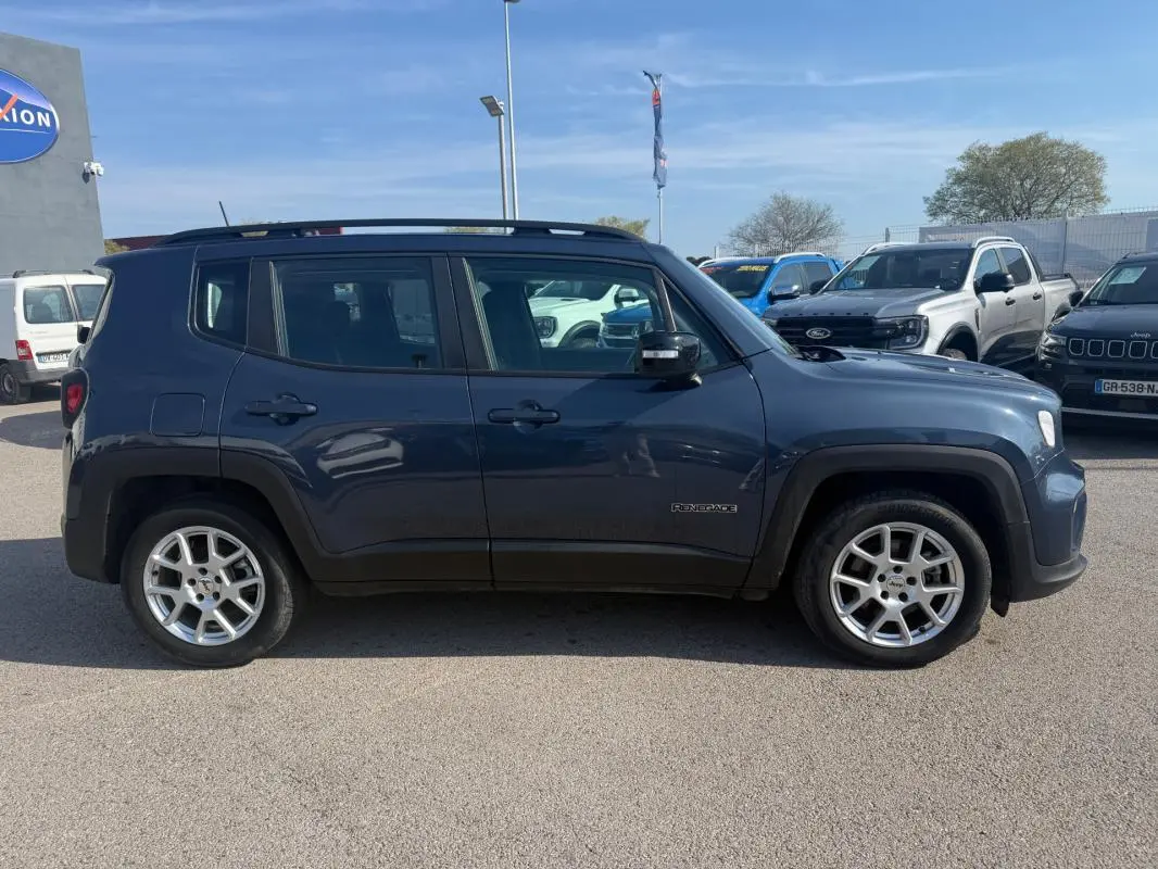 Vue latérale gauche d'un Jeep Renegade bleu 2023 avec jantes alliage et barres de toit visibles.