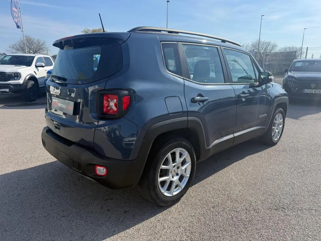 Jeep Renegade bleu vue 3/4 arrière droit, avec barres de toit et jantes alliage 17 pouces visibles.