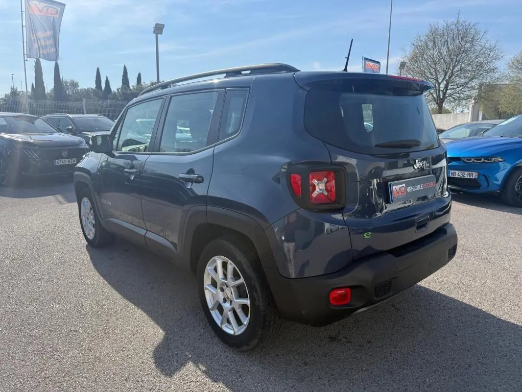 Jeep Renegade bleu vue 3/4 arrière droit, avec barres de toit et jantes alliage 17 pouces visibles.