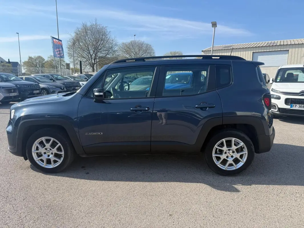 Vue de profil côté gauche d'une Jeep Renegade bleu 2023 avec jantes alliage 17 pouces et barres de toit noires.