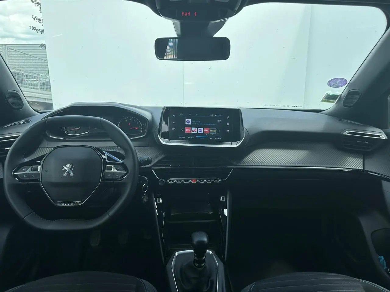 Vue intérieure avant du Peugeot 2008 gris clair 2022 avec tableau de bord carbone et écran tactile 7 pouces.