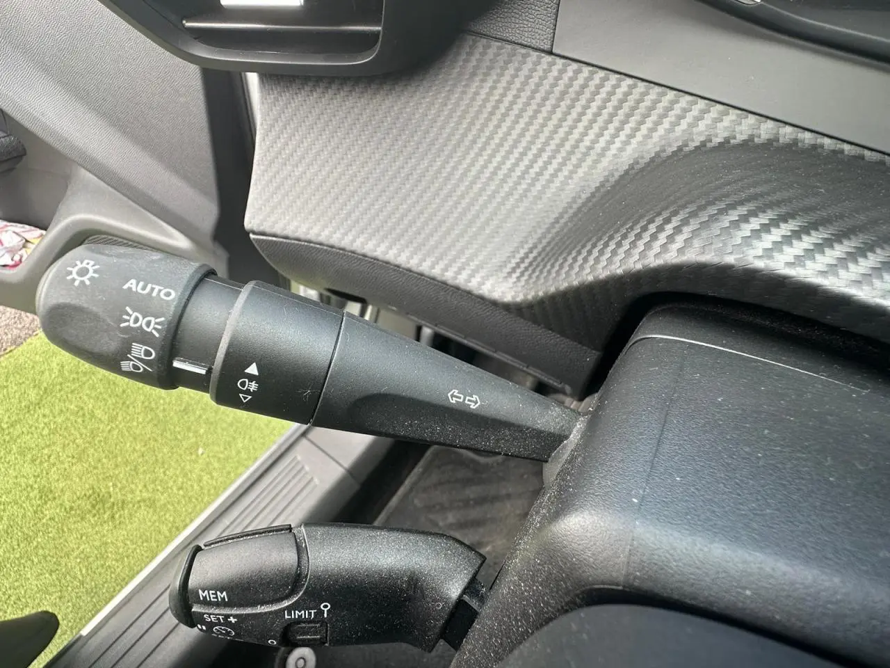 Détail des commandes de phares et régulateur sur la colonne de direction d'un Peugeot 2008 gris clair 2022.