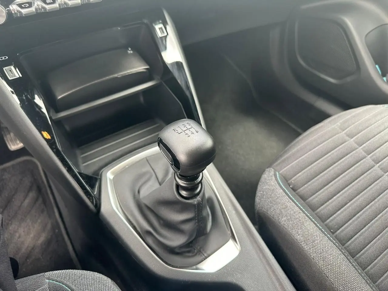 Le levier de vitesses manuel noir et la console centrale brillante d'une Peugeot 2008 gris clair, vue côté droit intérieur.